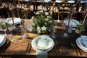 Rustic wooden table set for elegant dining with white floral centerpieces and vintage-style place settings.