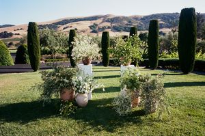 A scenic outdoor wedding venue in Tuscany with cypress trees and rolling hills in the background.