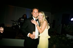 People in formal attire celebrate at a social gathering with drinks and smiles.