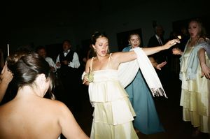 Wedding guests dance together in a dimly lit reception venue with warm ambient lighting.
