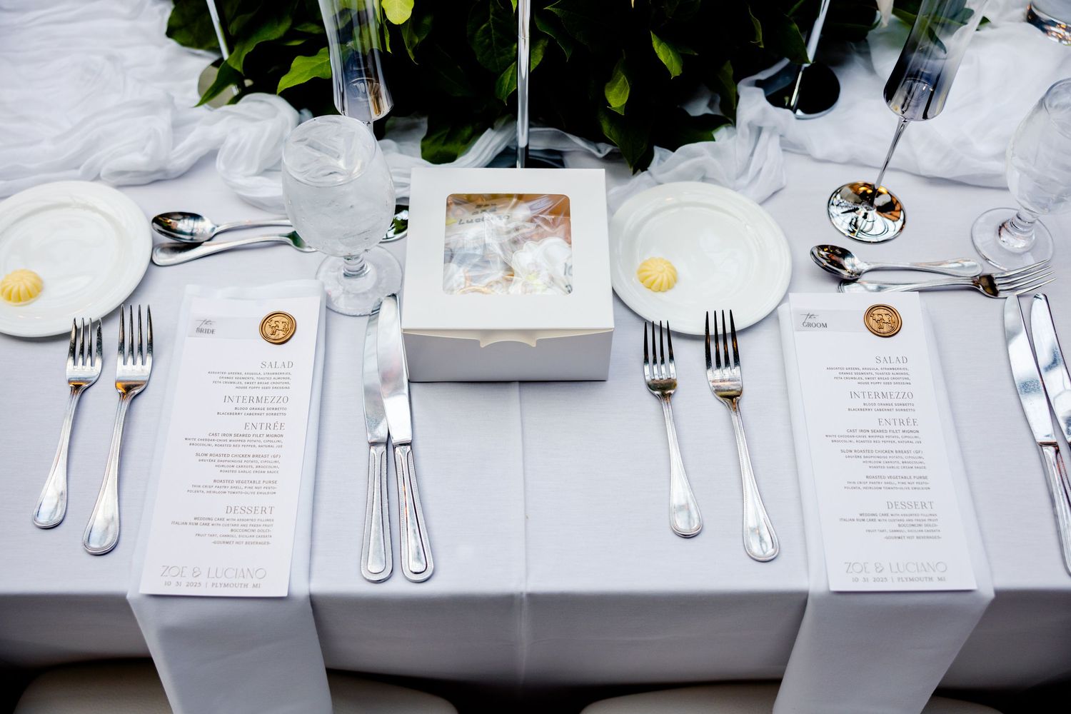 Elegant table settings with white linens, silverware, and menu cards arranged in a formal dining setup at a restaurant.