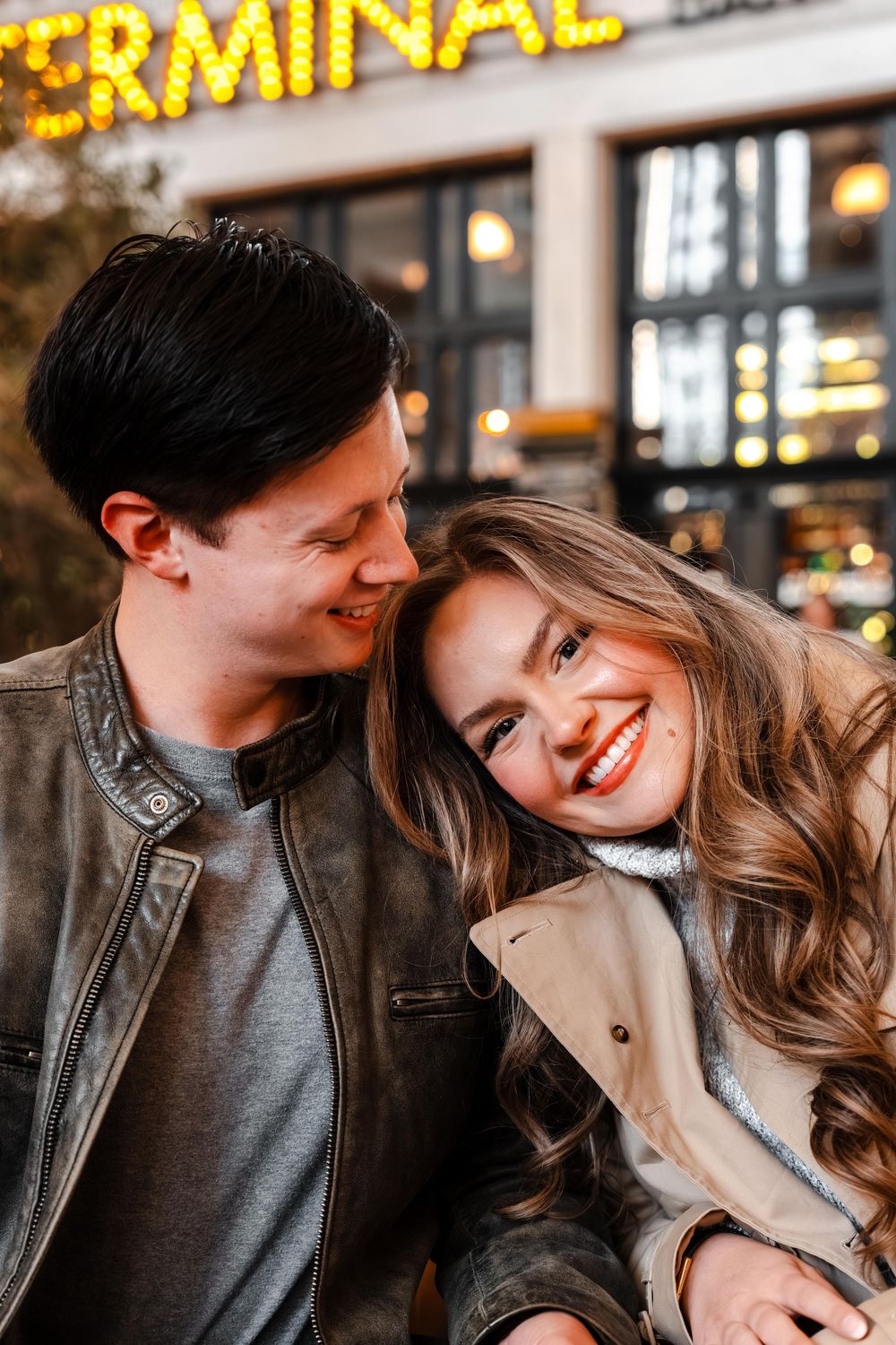 Cheerful couple snuggling close together outside the Terminal Bar at night.
