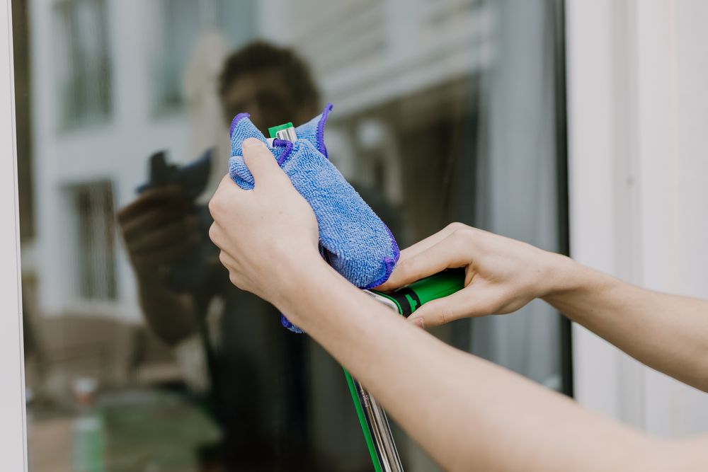 Two hands cleaning the window wiper with a cloth.