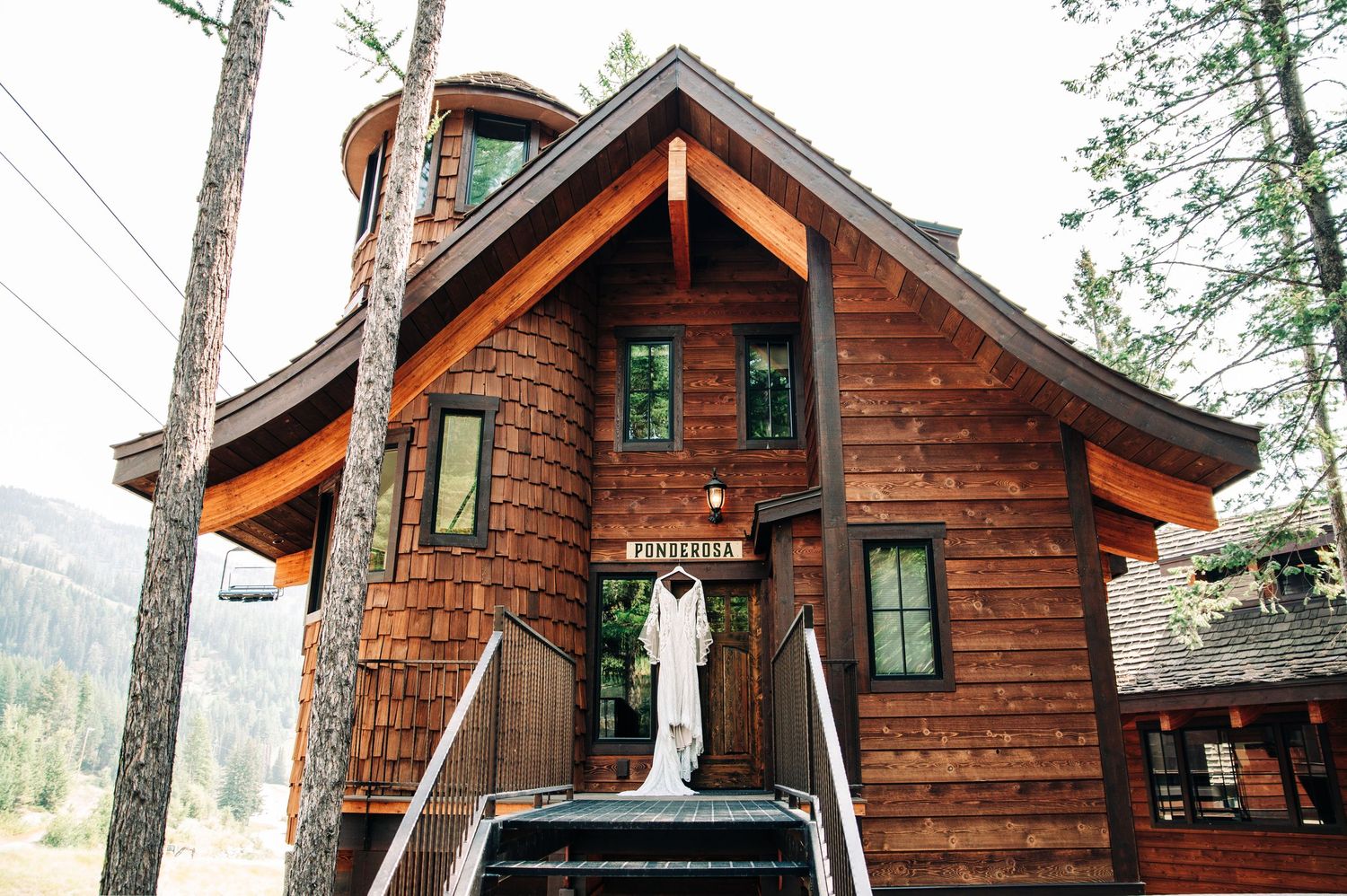 A row of rustic wooden log cabins nestled among trees at a mountain resort property.