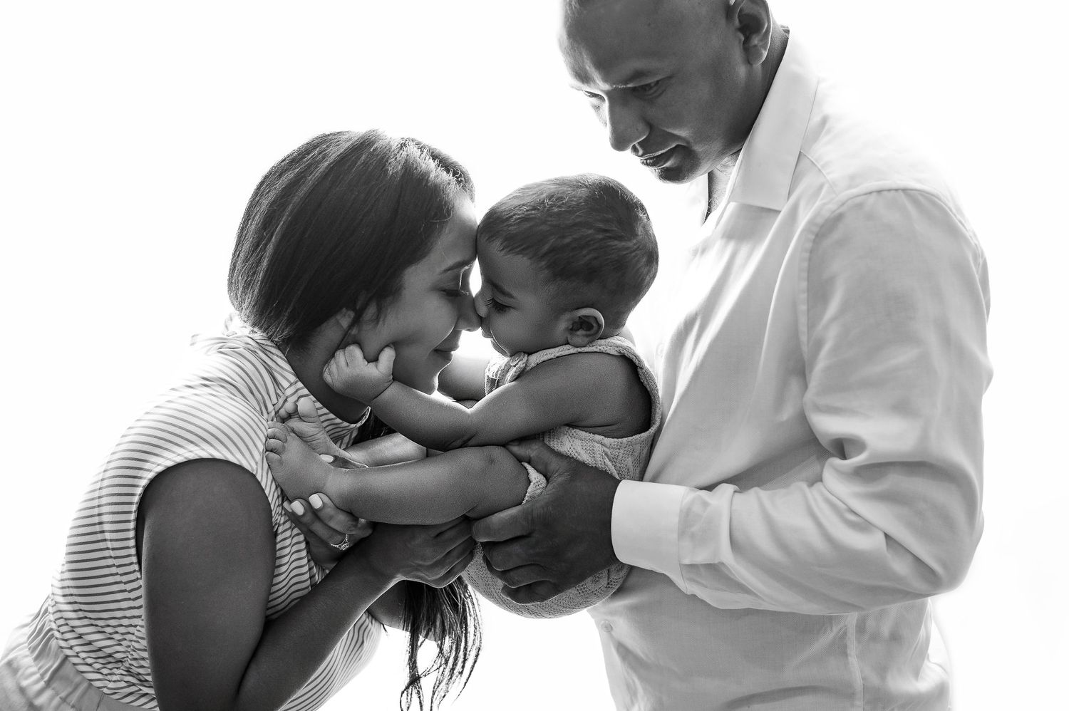 Black and white photo series showing intimate moments between parents and newborn babies in tender embraces.