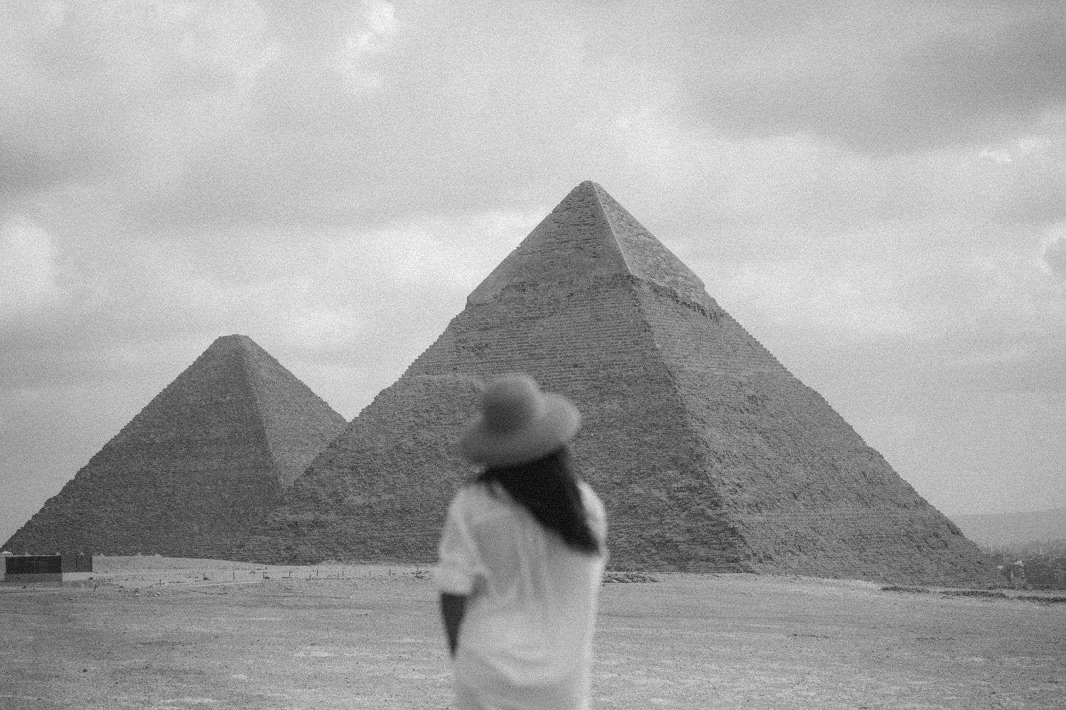 Ancient Egyptian pyramids of Giza photographed in black and white under dramatic cloudy skies.
