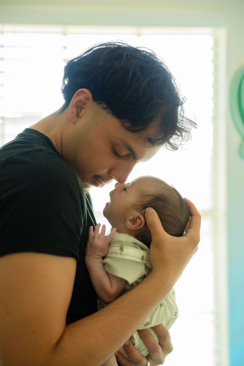 Father holding newborn son in childhood home during Houston lifestyle session