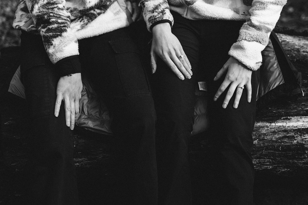 Black and white photograph showing hands in white sleeves resting on a textured surface.