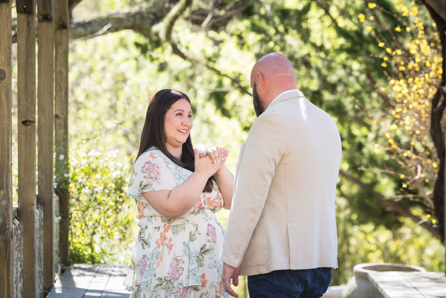 A couple shares a joyful moment together on a sunny porch surrounded by greenery.