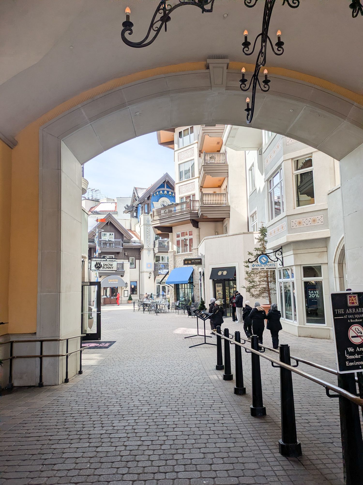 Panoramic view of a historic European cobblestone street with beige buildings and ornate architecture.