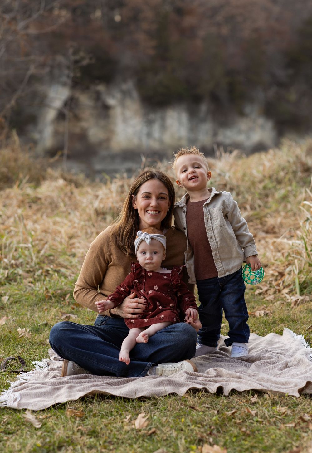 A heartwarming outdoor family photoshoot series with mother and child sitting on a blanket in autumn.
