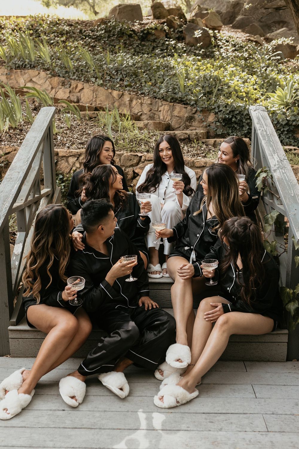 Group in matching black silk robes and slippers lounging together on outdoor bench in candid sequence at The Oaks at Duncan Lane.