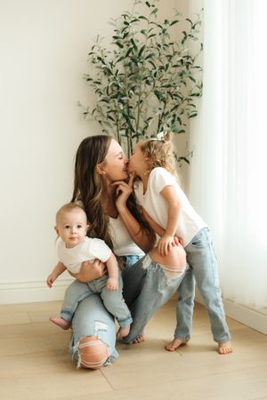 Candid family moment with casual styling against white wall and indoor plant.