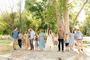 Extended family gathering outdoors among trees wearing coordinated casual outfits in Saratoga Springs, Utah