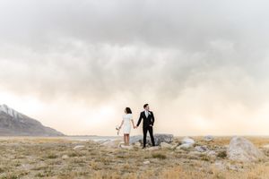 Silhouetted couple walking along a misty mountain ridge at sunset.