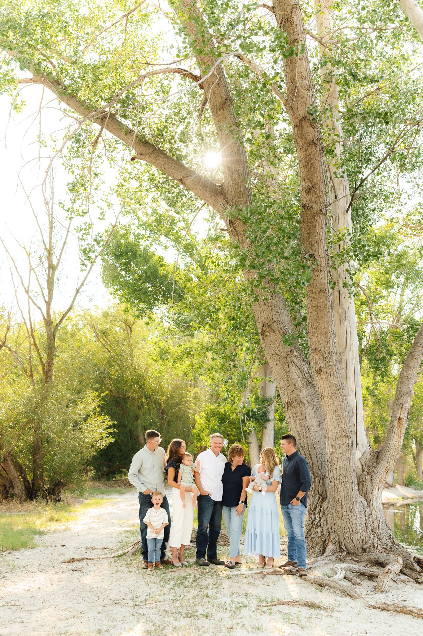 Wedding party gathered under large cottonwood trees in a natural outdoor setting.