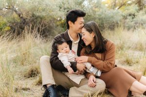 Casual outdoor family photoshoot with natural poses and warm earth tones.