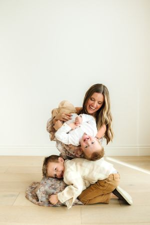 Playful lifestyle photography session with parent and child on wooden floor.