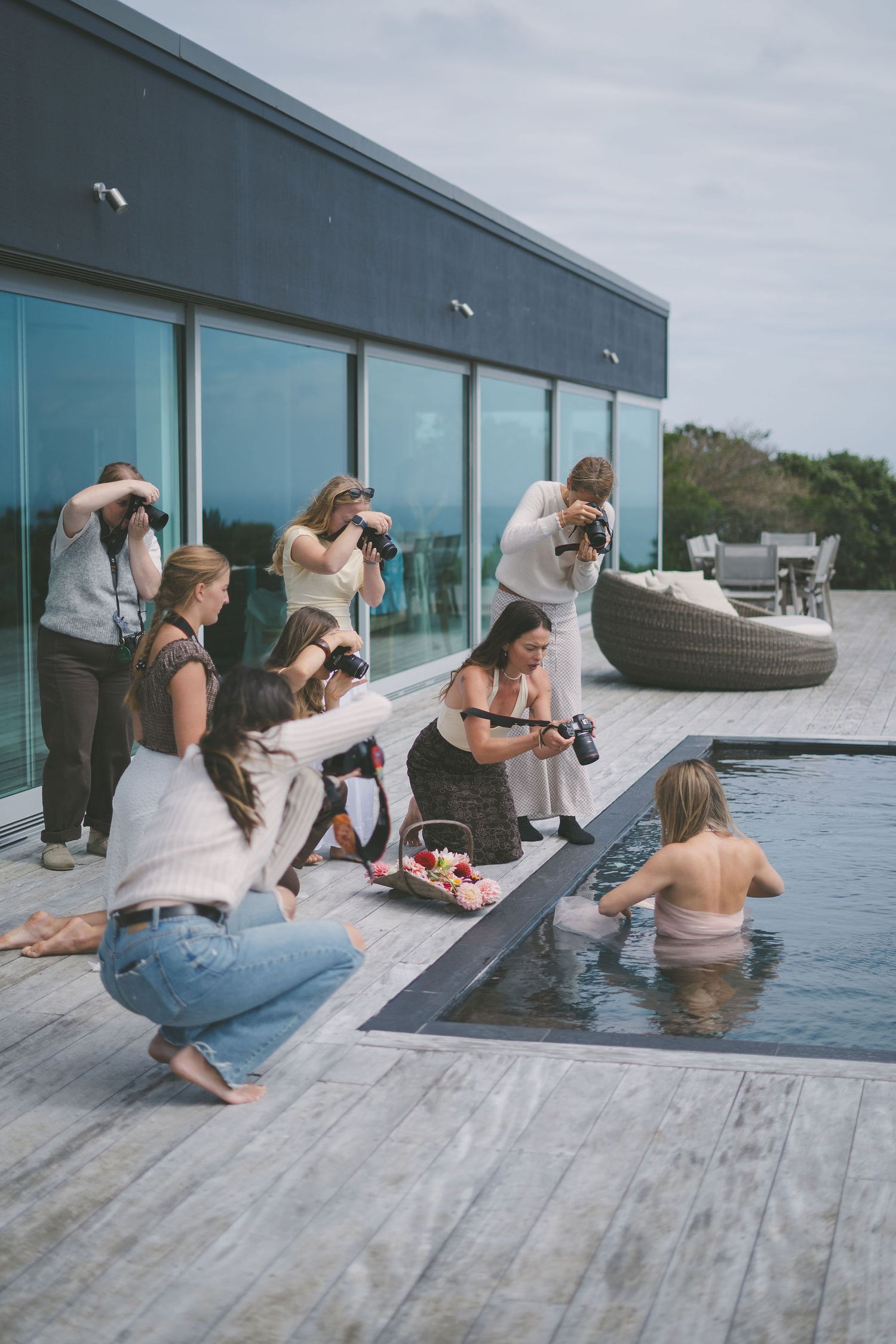 Photography workshop participants photographing a woman in a pool on a modern outdoor deck.