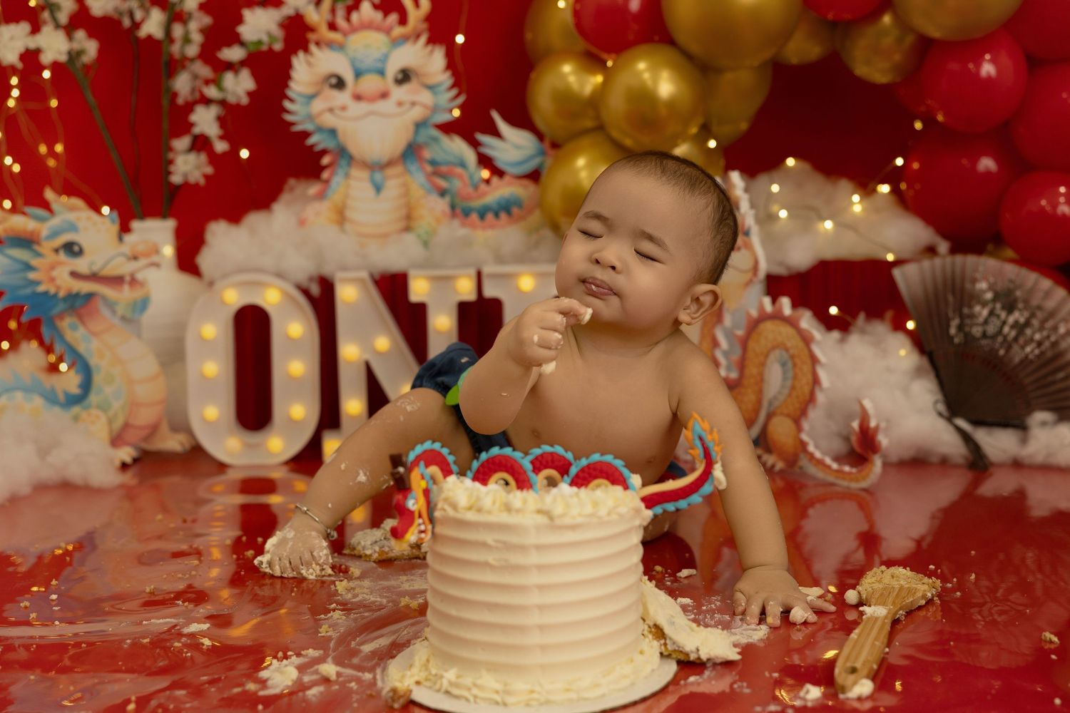 Birthday cake display with red and gold decorations and twinkle lights creating a magical atmosphere.