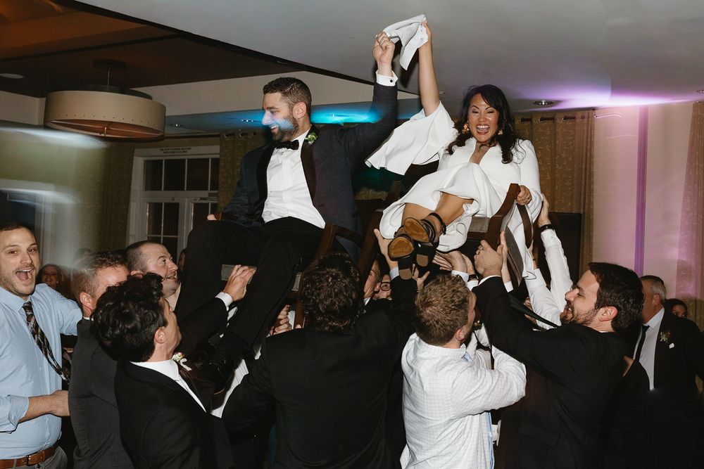 Wedding guests dance and celebrate on a dimly lit dance floor during an evening reception.
