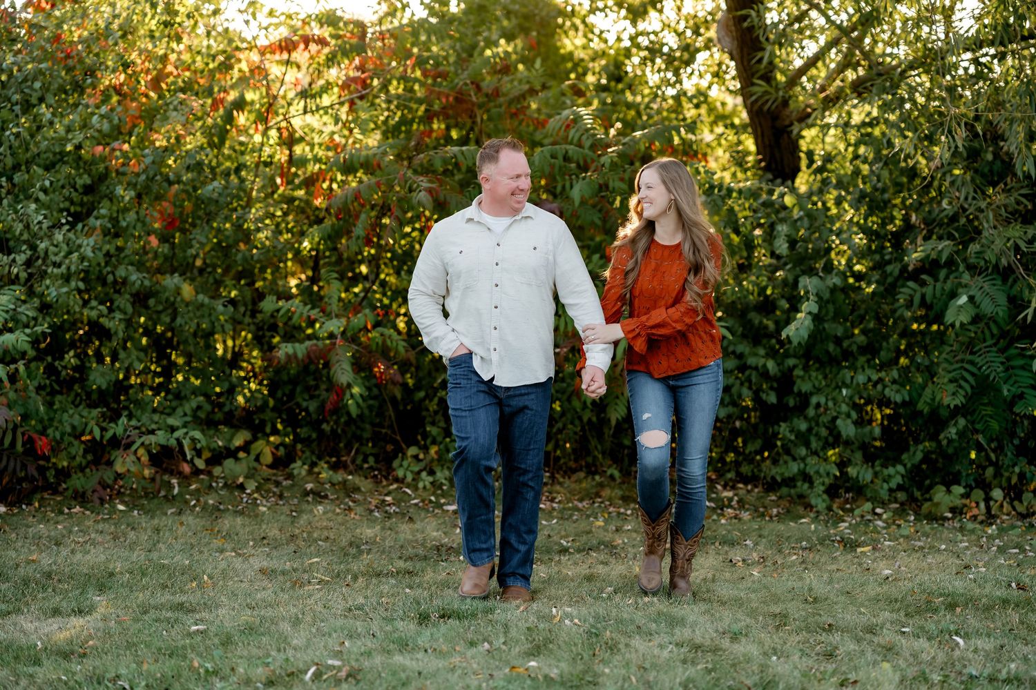 Two people walk together through an autumn garden setting with golden sunlight filtering through trees.