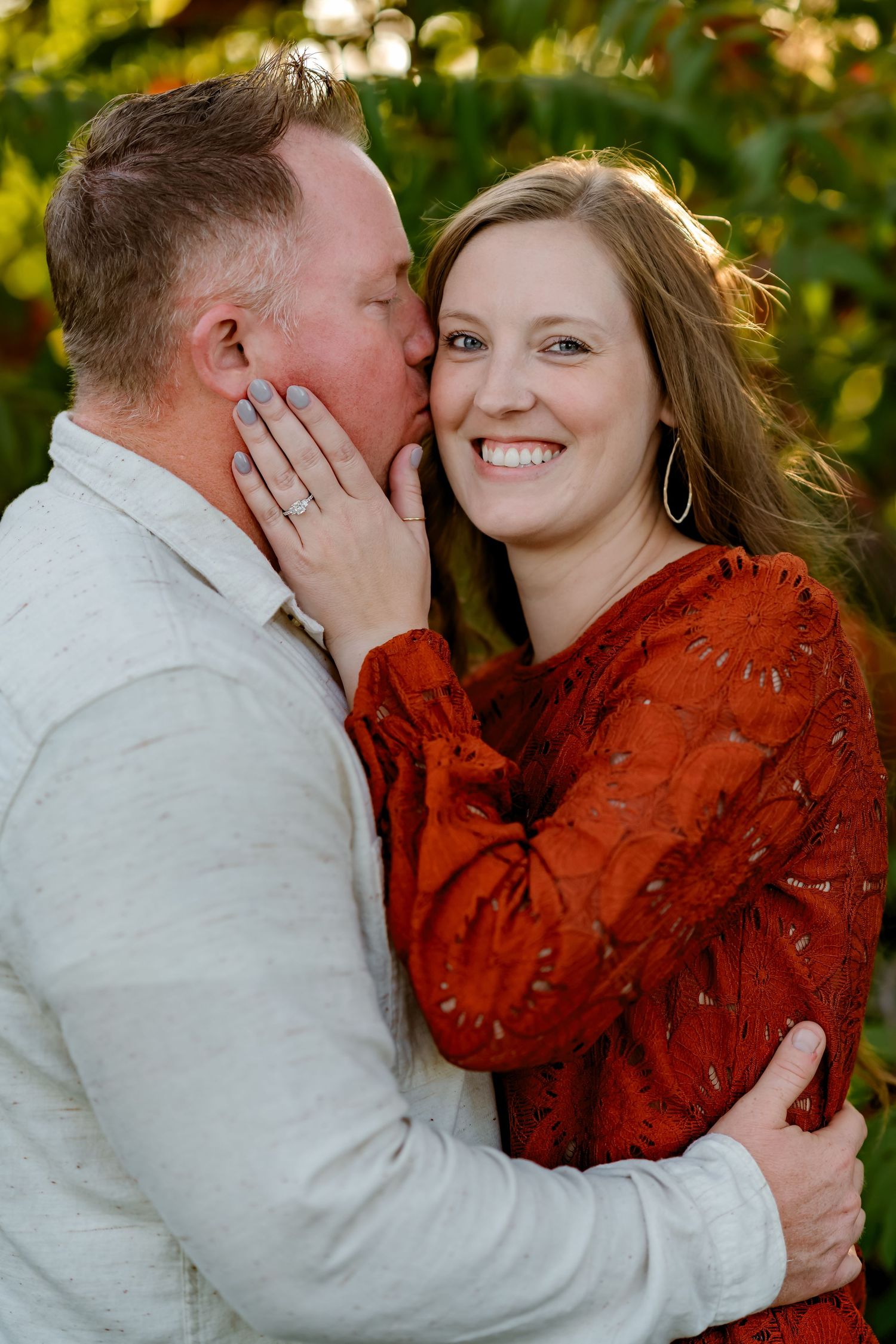 A couple shares intimate moments in a romantic outdoor photoshoot at golden hour wearing red and white outfits.
