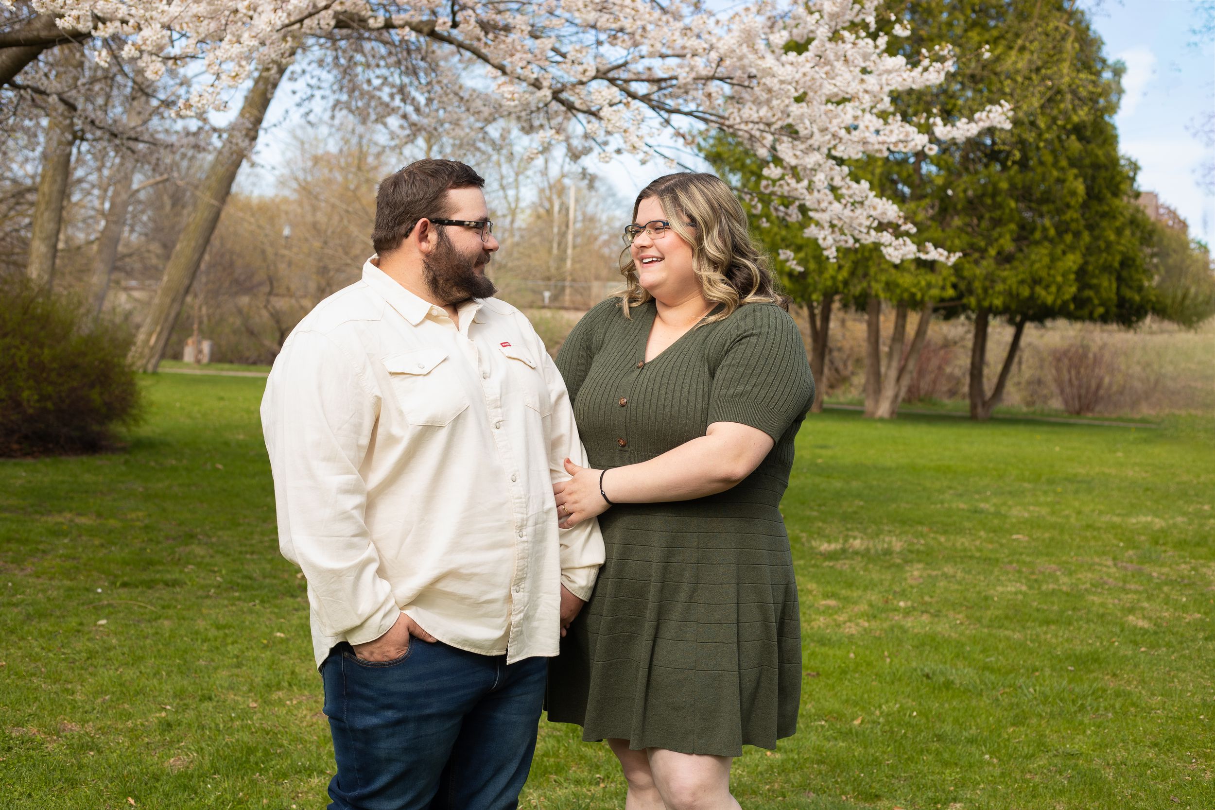 A couple shares a romantic moment under blooming cherry blossom trees in a spring garden setting.