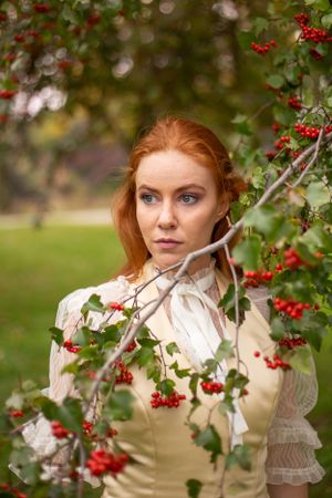 Portrait among red berries and branches featuring vintage-inspired styling and natural lighting.