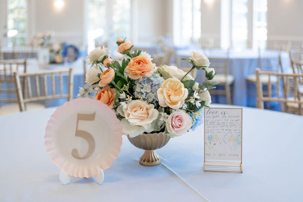 Wedding reception table settings with numbered signs and delicate floral arrangements in soft pastels.  DALLAS WEDDING PHOTOGRAPHER