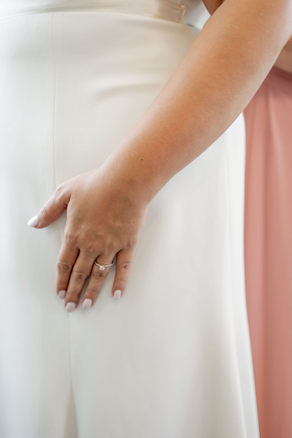 Close-up of hands wearing an elegant engagement ring against a white dress. DALLAS WEDDING PHOTOGRAPHER