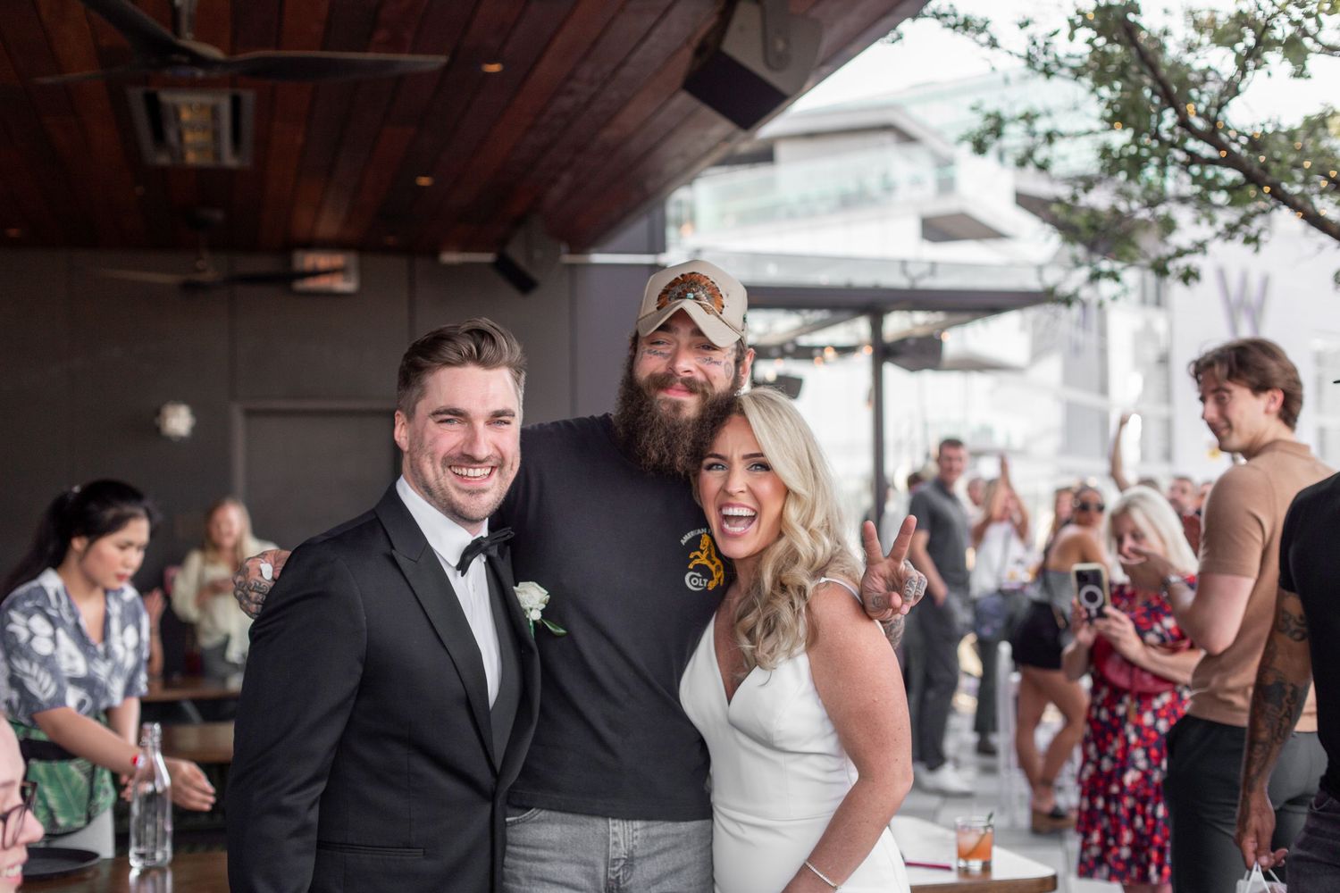 Wedding guests mingle and celebrate during an outdoor reception on a covered patio. NASHVILLE WEDDING PHOTOGRAPHER