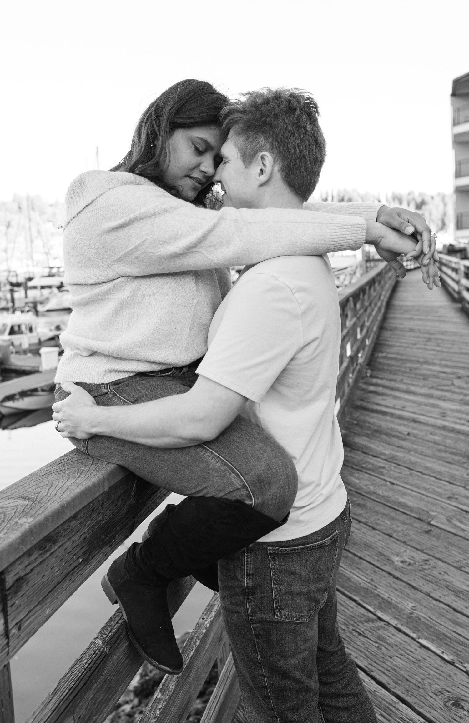 A romantic black and white photo series of a couple embracing and kissing on a wooden dock.
