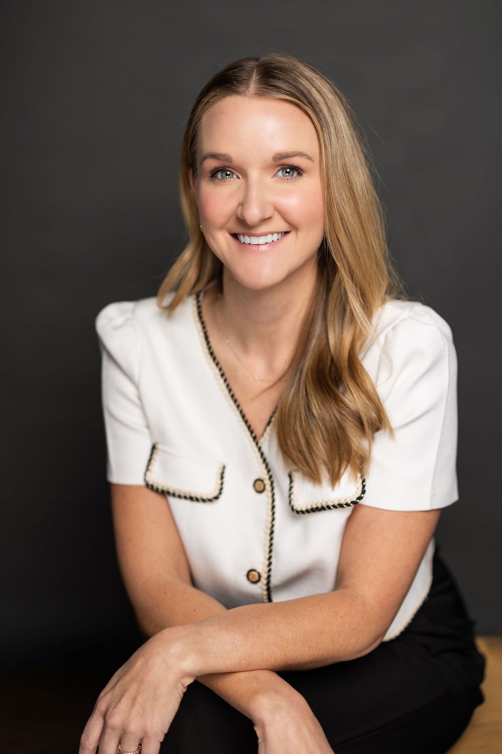 Stylish business headshot showing a white blouse with contrasting trim in professional lighting.