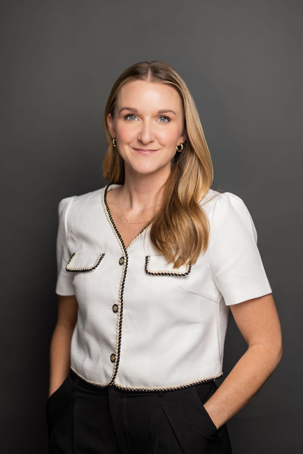 Professional studio portrait featuring a white collared top with black trim against a dark background.