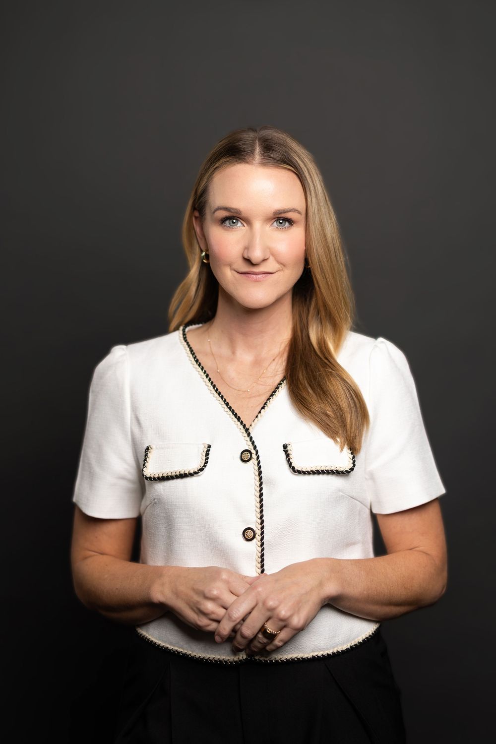 Elegant studio portrait highlighting a white top with black trim detail and professional styling.