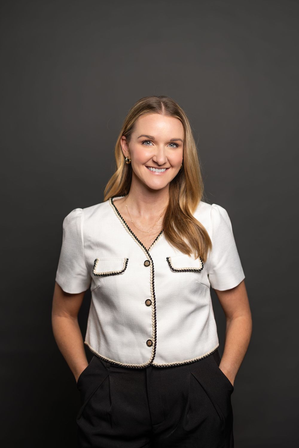 Professional portrait showcasing a classic white and black outfit with decorative trim details.