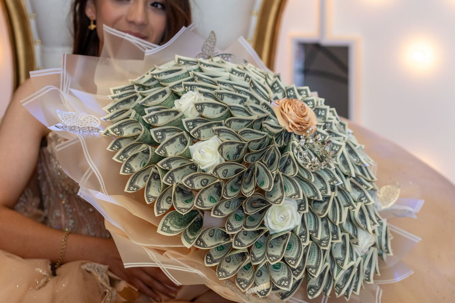 A creative money ramos made from folded dollar bills arranged in a circular pattern with white flowers.