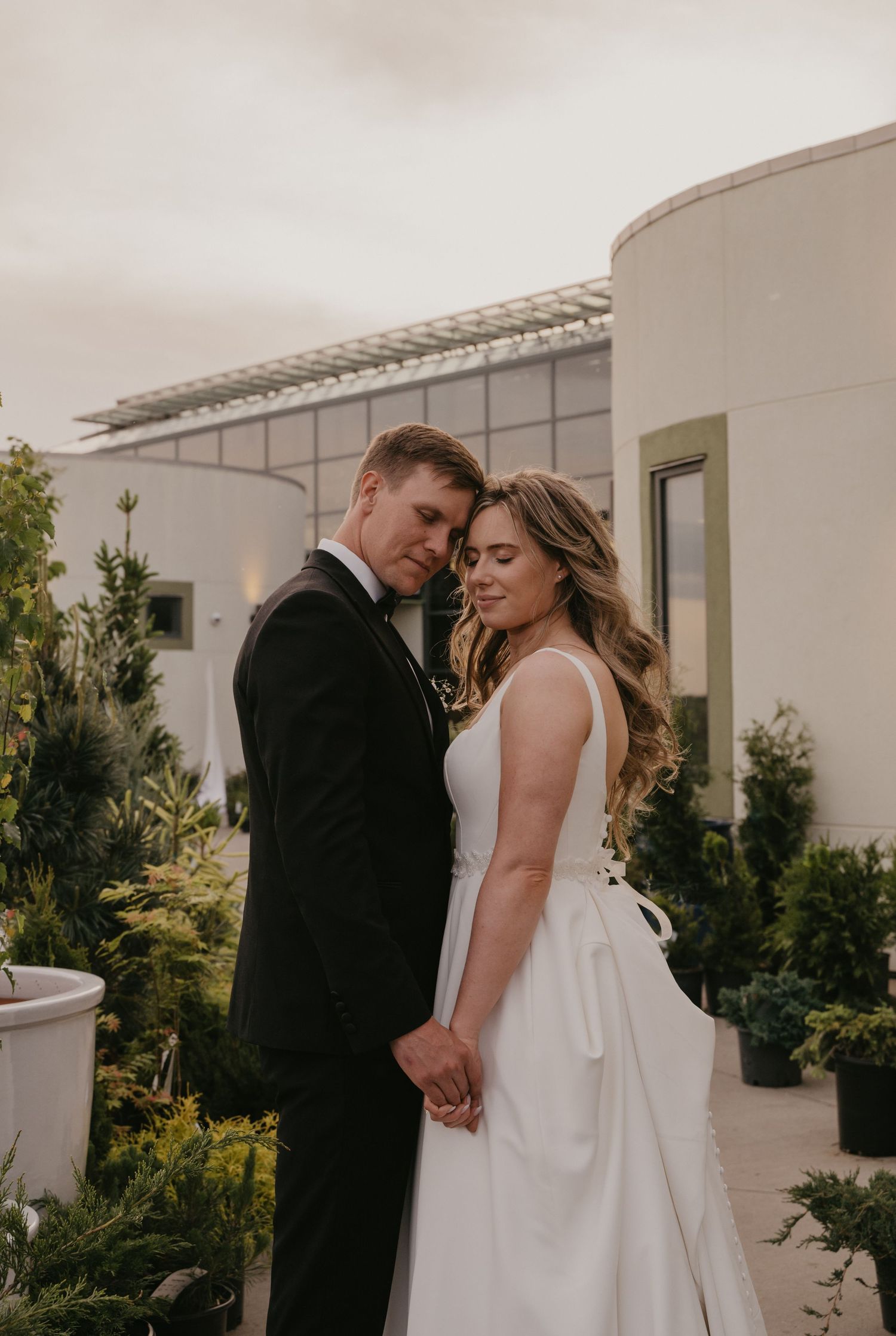 A romantic wedding couple shares intimate moments in a series of black and white photos against a white building exterior.