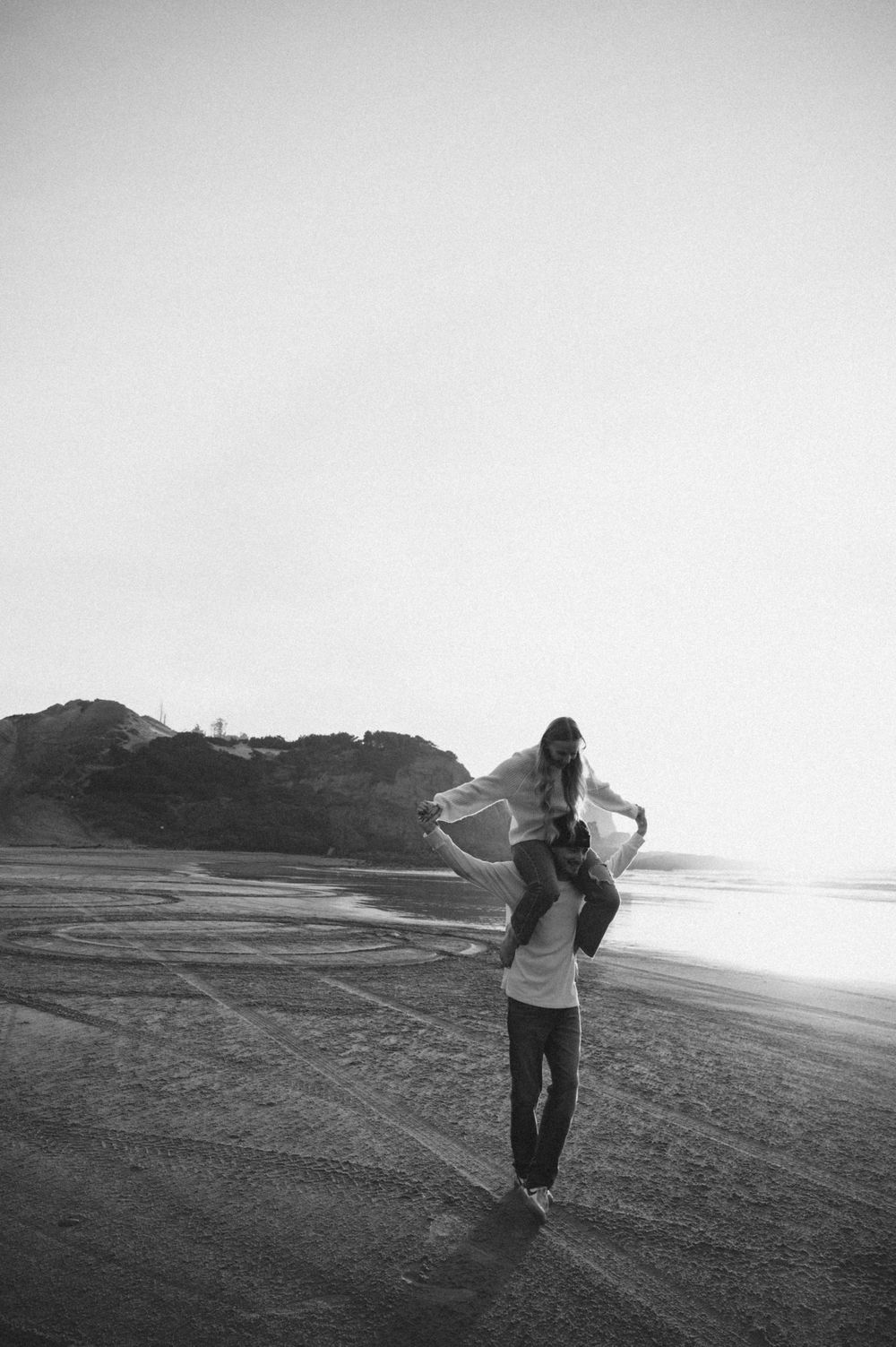 Silhouettes dancing on a misty beach with dramatic cliffs in the background.