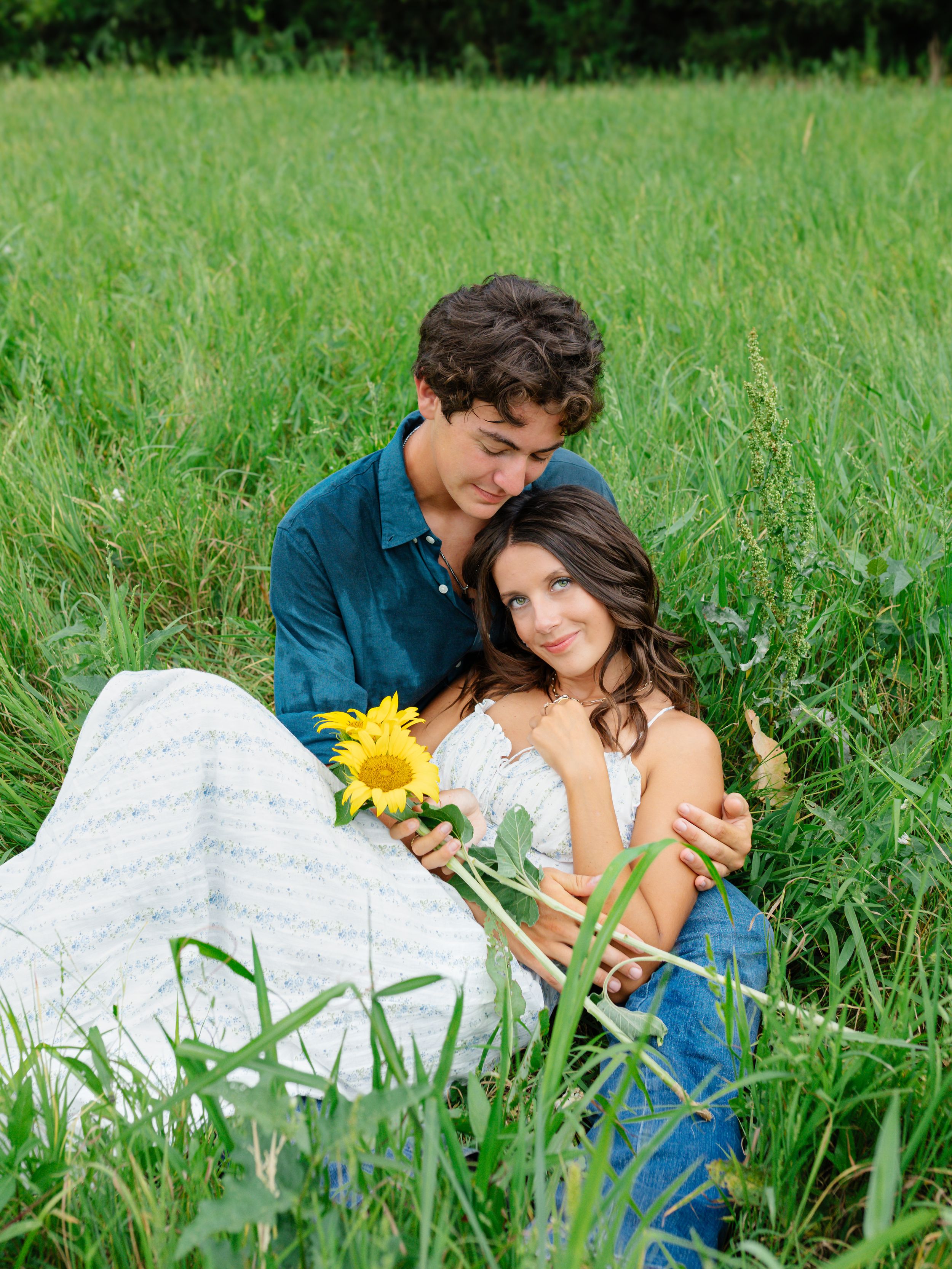 Couple relaxing in tall grass field with sunflower.