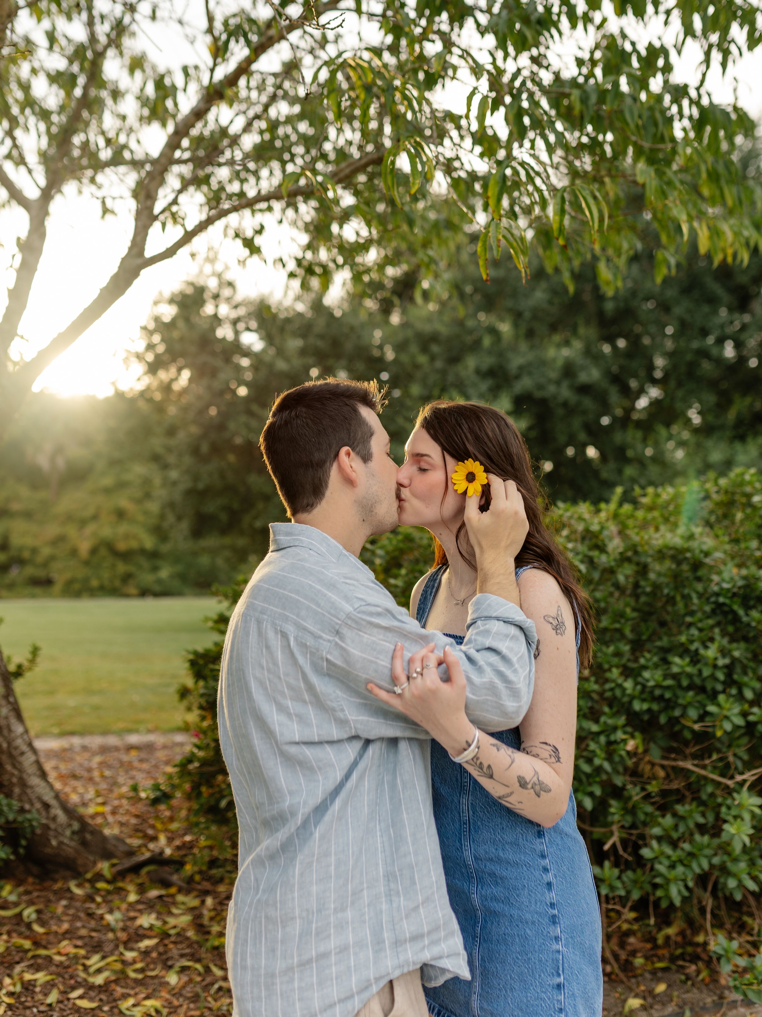 Romantic couple sharing a tender moment in a sunlit garden setting.