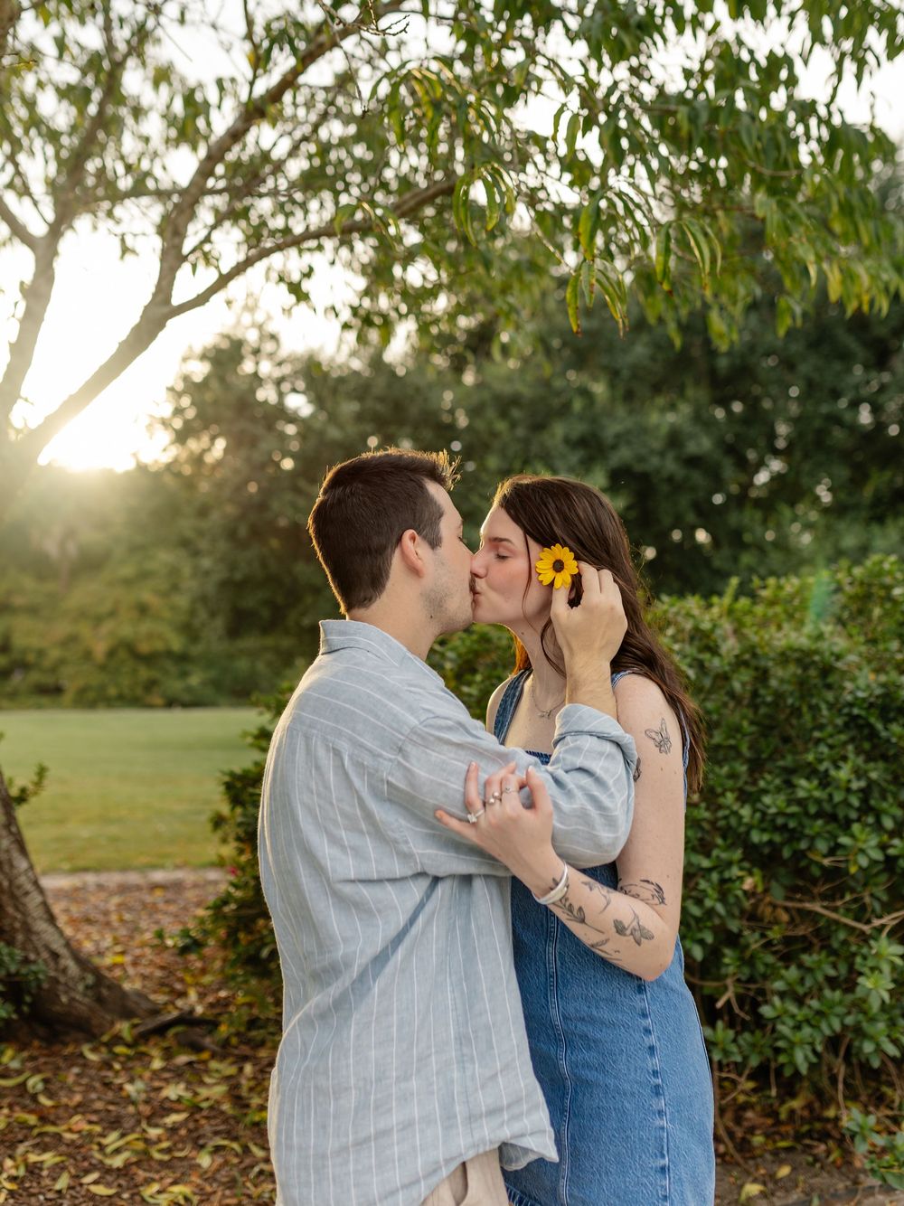 Romantic couple sharing a tender moment in a sunlit garden setting.