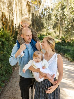 Family of four poses together on a path lined with Spanish moss.