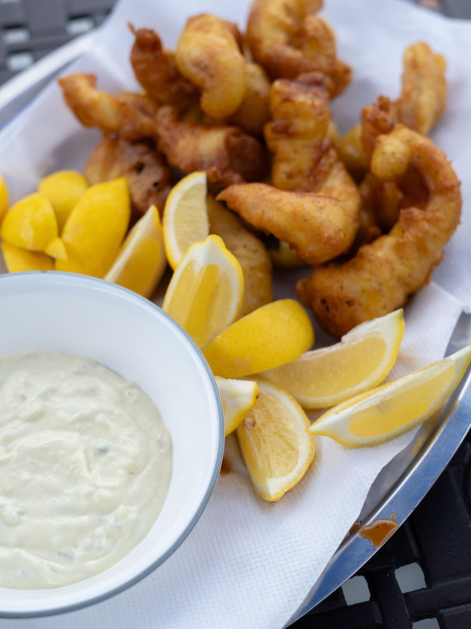 Crispy fried shrimp served with tartar sauce and fresh lemon wedges on a white plate.