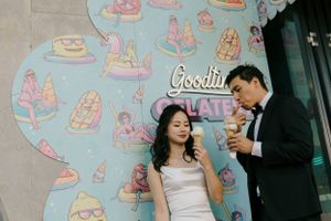 A couple shares a moment outside a cafe wall decorated with colorful ice cream and dessert illustrations.