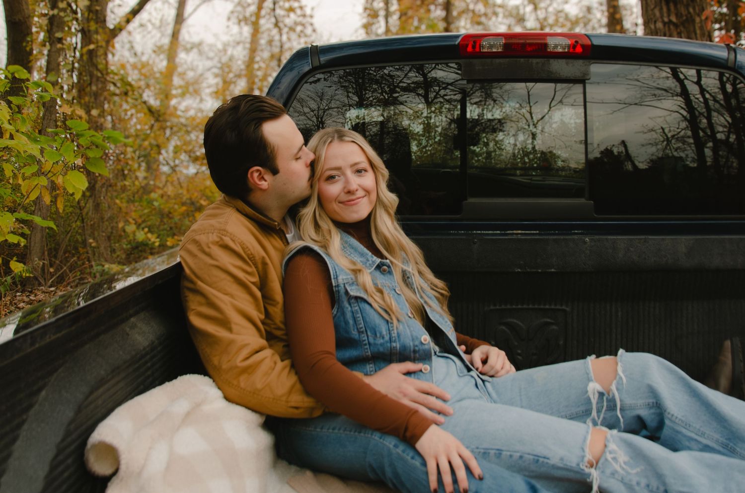 A couple shares tender moments in an autumn forest setting during a romantic outdoor photoshoot.