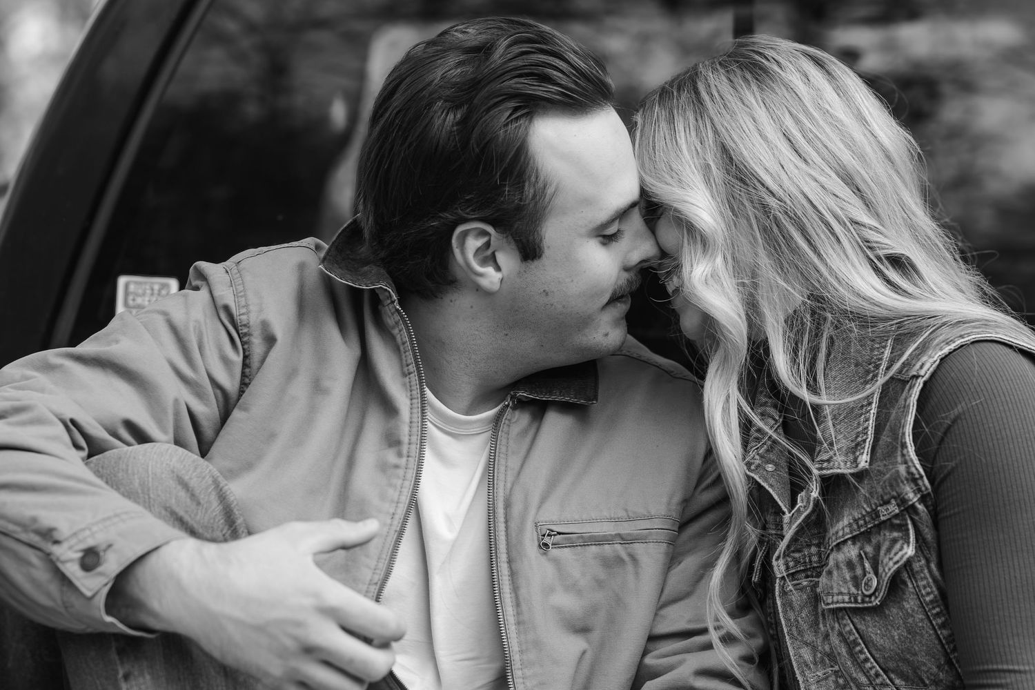 Black and white intimate portrait of couple sharing tender moment outdoors.