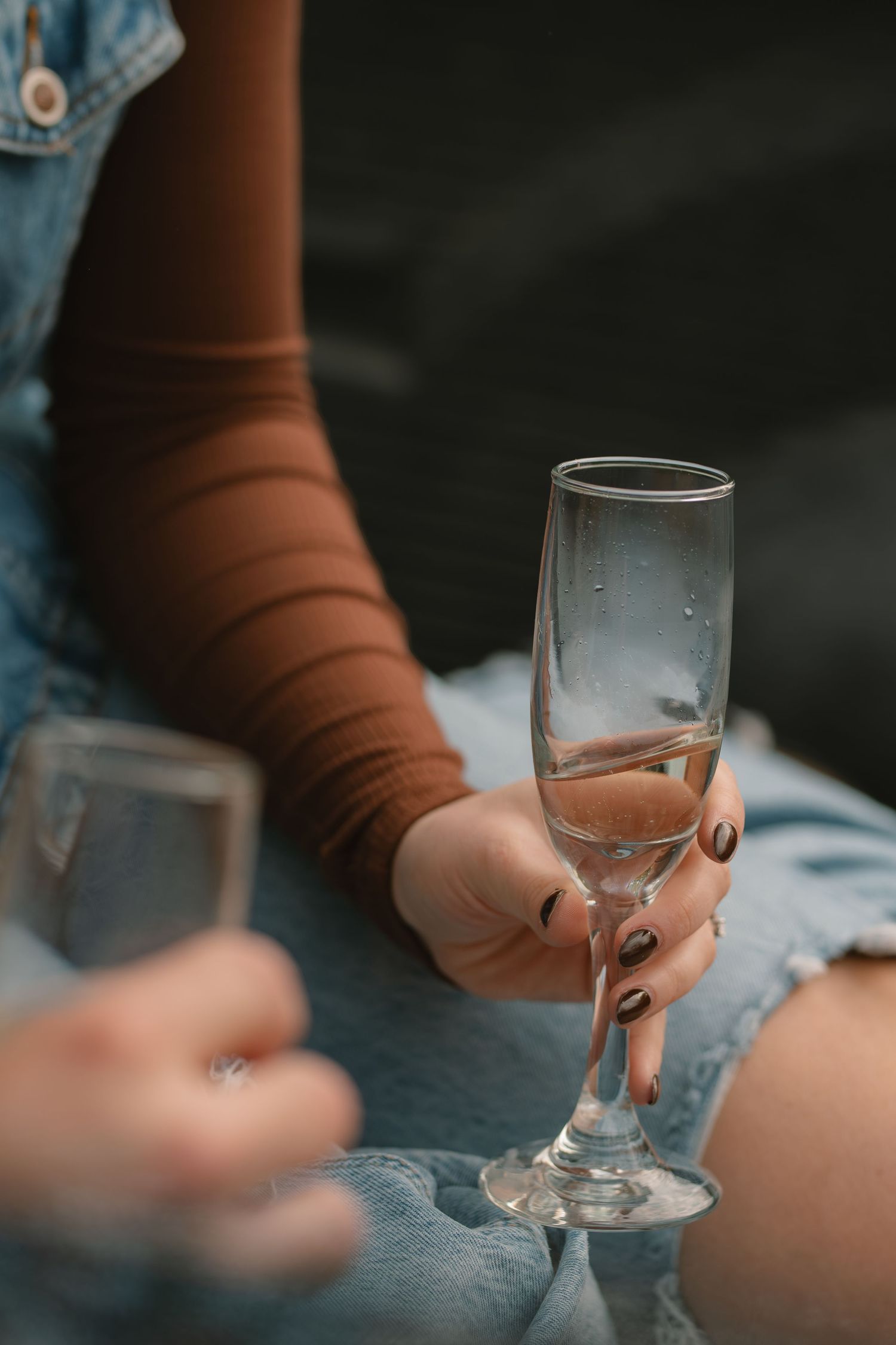 A hand holding a wine glass in a dimly lit setting shows multiple frames in a cinematic sequence.