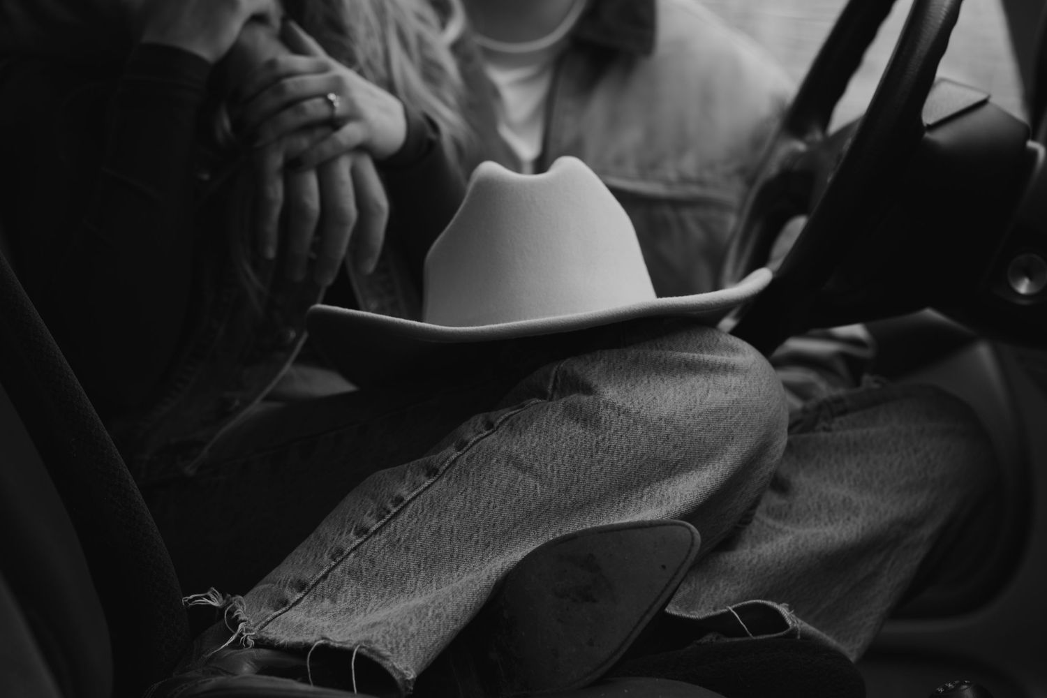 Close-up black and white shot of hands holding book while sitting together.